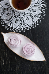 Handmade berry marshmallow, cup of tea and a white wipes on a black vintage wooden background.