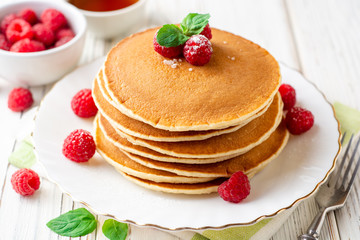 Pancakes with raspberry and mint on white wooden background