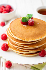 Pancakes with raspberry and mint on white wooden background