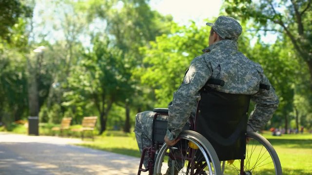 Injured soldier in wheelchair moving in park, social military support, pension