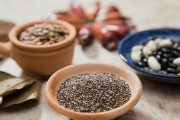 Composition with rustic pottery bowls of chia seeds, Lentils, and beans. Pinions and 'Castanha-do-Pará' nuts. Laurel Nobilis aromatic leafs