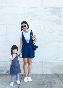 Toddler with auntie in matching overalls by marble wall