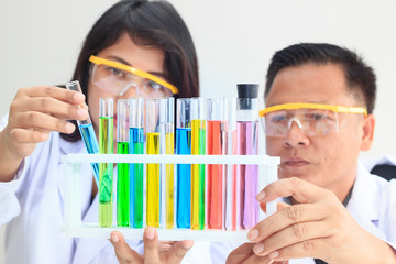 Young female and male scientist team examining with color test tube in laboratory for science research.Concept Science and Medical image.