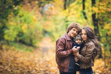 Young happy family hugging in autumn in park.