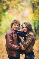 Young family hugging in autumn in park.
