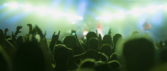 Sillhouettes of concert crowd in front of bright stage lights