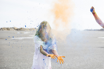 Male hand throwing blue and orange powder to young woman