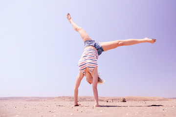 Girl gymnast on the background of the desert, walking on his hands. The concept of a healthy lifestyle, fitness.
