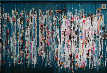 Grunge background with ripped posters on the wall of a metal container