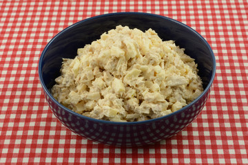 Albacore tuna fish salad made with chopped apple in blue serving bowl on red checkered tablecloth