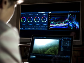 young man edit video in dark studio using color grading tools and modern equipment