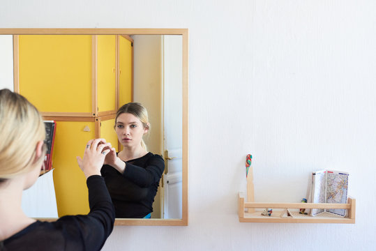 Girl touching mirror surface with arm.