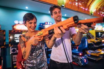 Couple playing shooting game at a gaming arcade