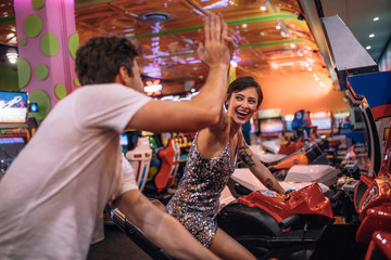 Couple playing racing games sitting on arcade racing bikes