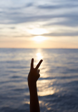 Child hand silhouette, outstretched fingers, sea sunset background