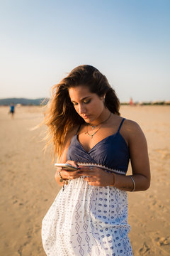 Young woman using a phone at the beach