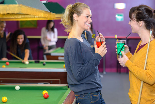 Ladies chatting with drinks in pool hall