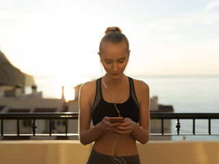 Fit woman listening to music on balcony