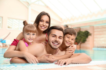 Naklejka premium Happy family resting in indoor swimming pool
