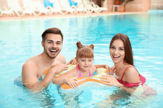 Happy family with inflatable ring in swimming pool