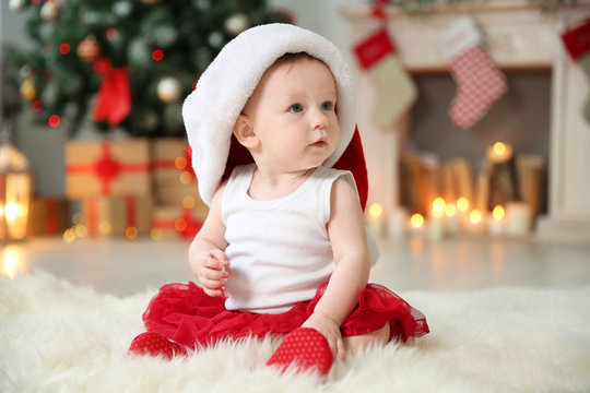 Cute baby in Santa hat on floor at home. Christmas celebration