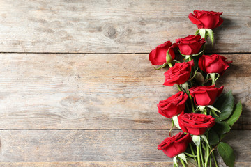 Fototapeta premium Piękne czerwone kwiaty róży na podłoże drewniane, widok z góry