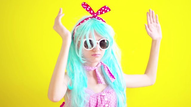 A girl in a blue wig wearing glasses in the image of an anime doll on