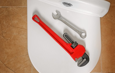 Different plumber's tools on toilet seat lid indoors