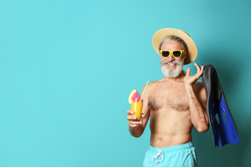 Shirtless man with glass of cocktail and flippers on color background © New Africa