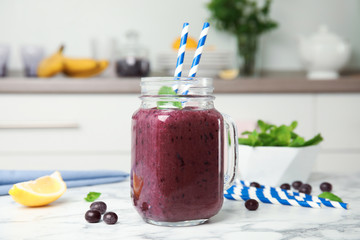 Mason jar with delicious acai smoothie on table in kitchen