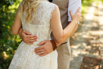 Wedding. Close-up view of stylish groom and beautiful bride embracing each other during walking outdoors.