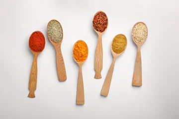 Foto op Canvas Composition with different aromatic spices in wooden spoons on white background © New Africa