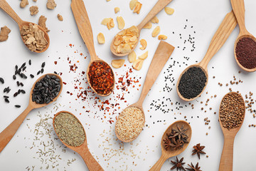 Composition with different aromatic spices in wooden spoons on white background