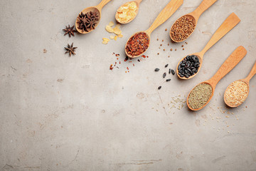 Flat lay composition with different aromatic spices in wooden spoons on gray background