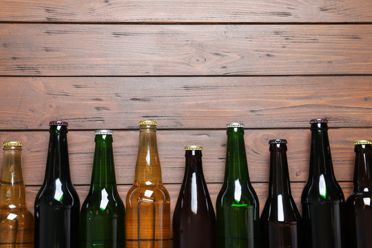 Bottles with different types of beer on wooden background