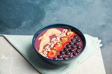 Bowl with tasty acai smoothie on gray table