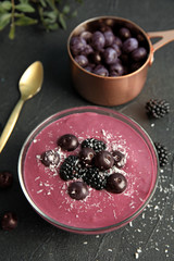 Bowl of tasty acai smoothie on dark table