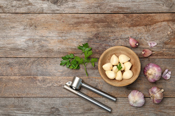 Flat lay composition with garlic press on wooden table