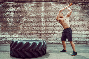 Sport Fitness Man Hitting Wheel Tire With Hammer Sledge Crossfit Training, Young Healthy Guy Gym...