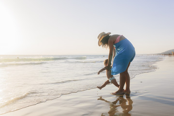 Mother helping her baby in his first steps