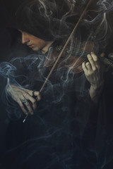 Dark phantom violin player, man performing a concert shrouded in smoke and fog