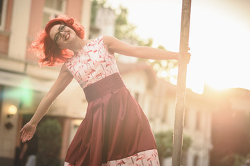 Young woman enjoying life, feeling playful on the streets, dancing next to a street sign