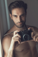 Sexy nude man, an amateur photographer, holding an slr camera