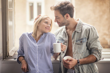 Beautiful and cute couple drinking their morning coffee or tea, affectionate and deeply in love,...