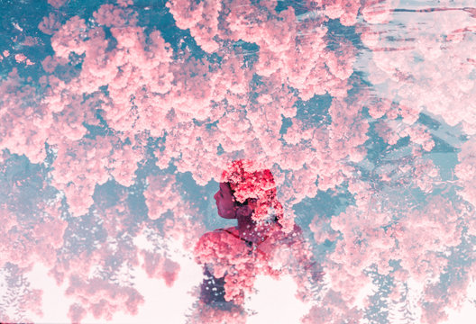 Woman standing in pool water covered in pink flowers