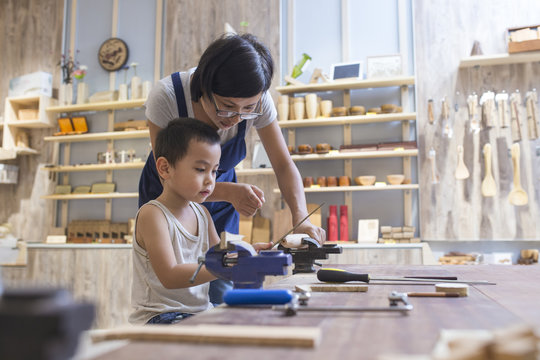 Asian womant with her kid doing carpenter job in the studio