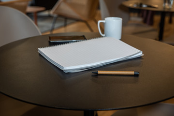 Pen on a round desk with note pad and coffee mug