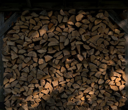 Chopped wood stacked with beams of sunlight falling on it.