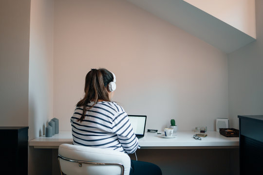Anonymous Woman With Headphones Working on a Laptop