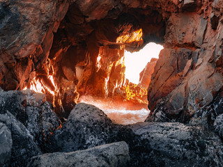 Close-up shot of sunlight coming through the rock hole at Pfeiffer Beach near Big Sur, California. Wave splashes are visible at the bottom of the stunning natural cave.